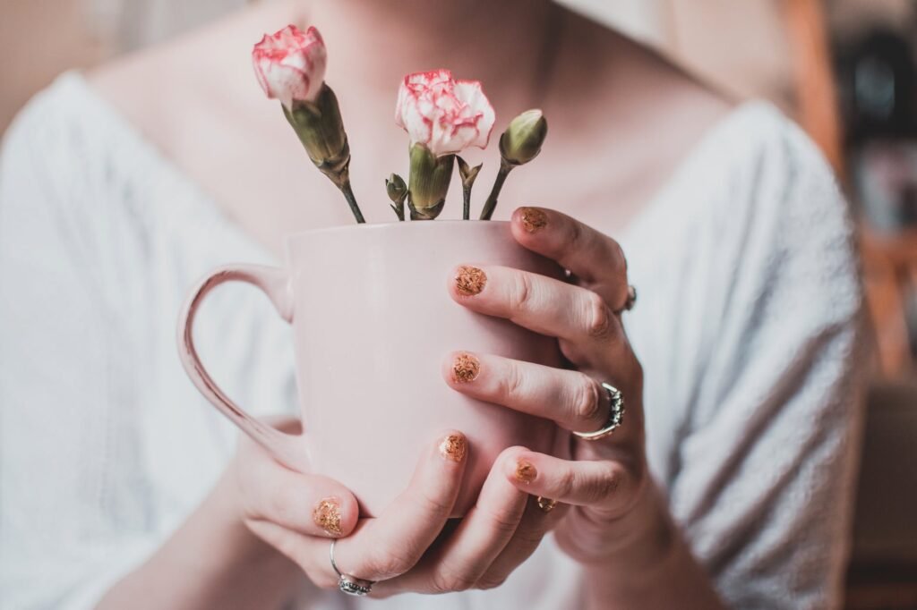woman wearing white shirt holding pink mug with white petaled flowers